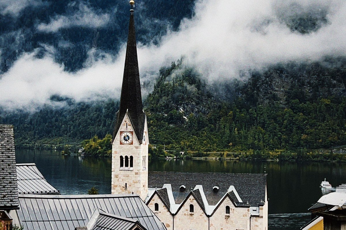 Hallstatt Austria winter fog over lake with snow-dusted alpine village reflection