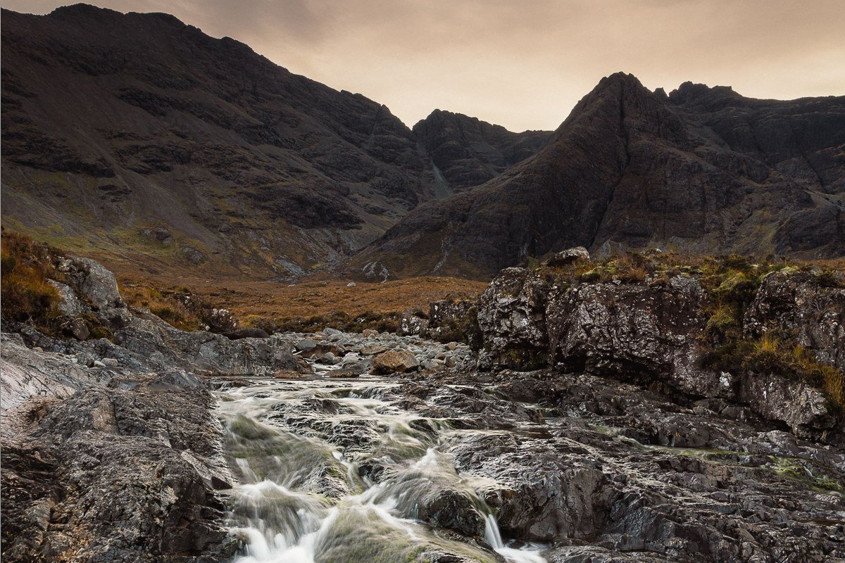 Isle of Skye Scotland misty fairy pools with moss-covered rocks and brooding sky