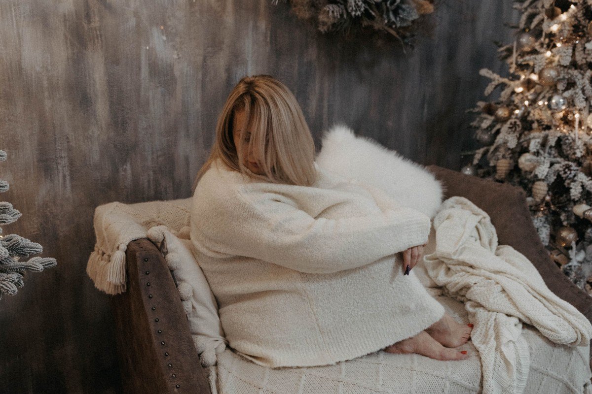 chunky oatmeal cardigan woman wrapped in blanket lakehouse window coffee