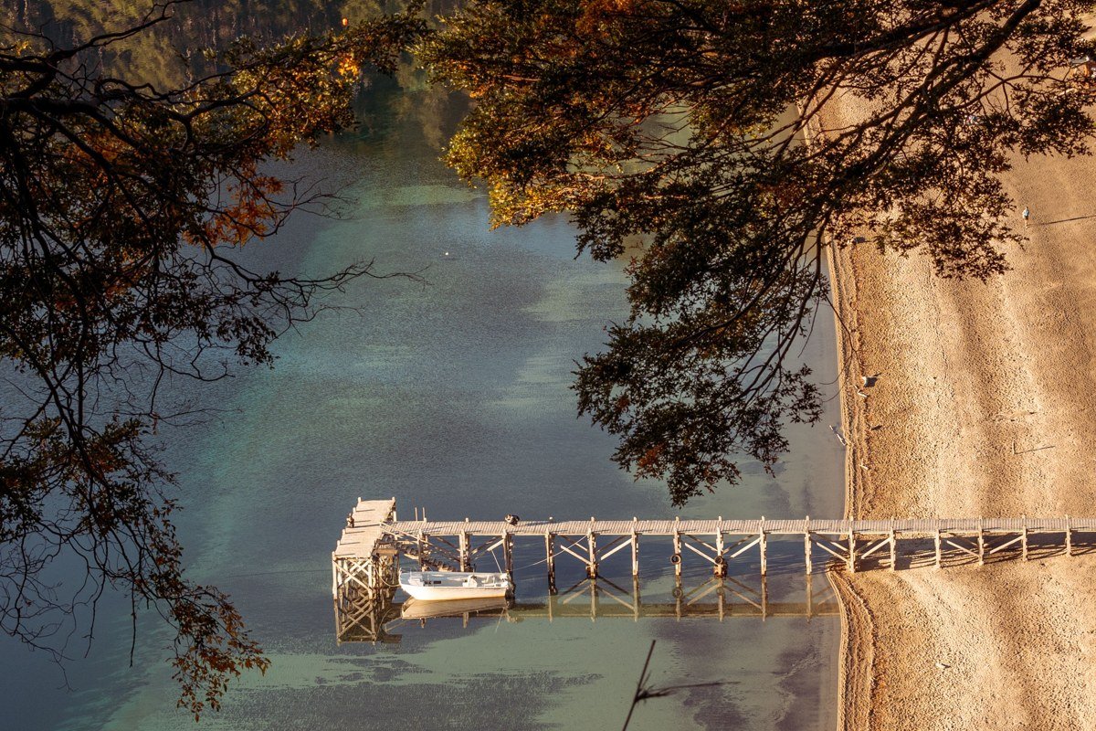 aerial view of a New England lake town in summer with forested shoreline and wooden docks