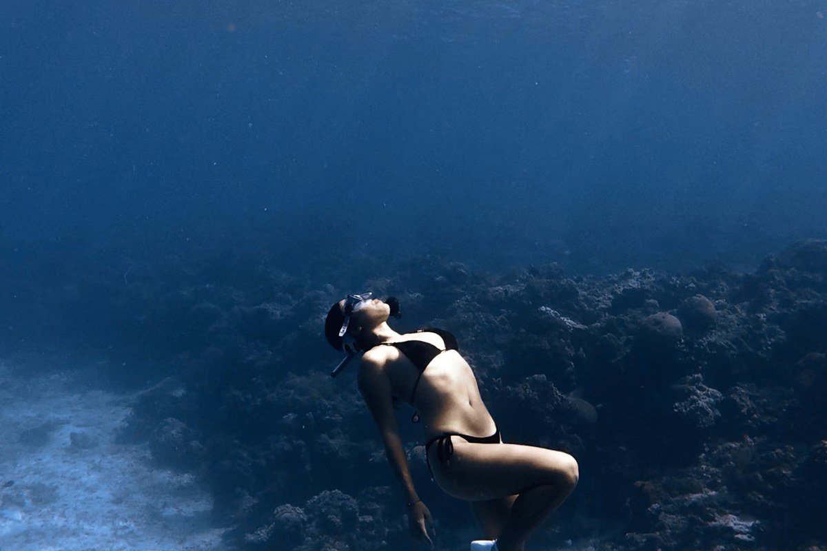 freediver descending into deep blue water of Dahab Blue Hole Egypt with coral arch visible below surface