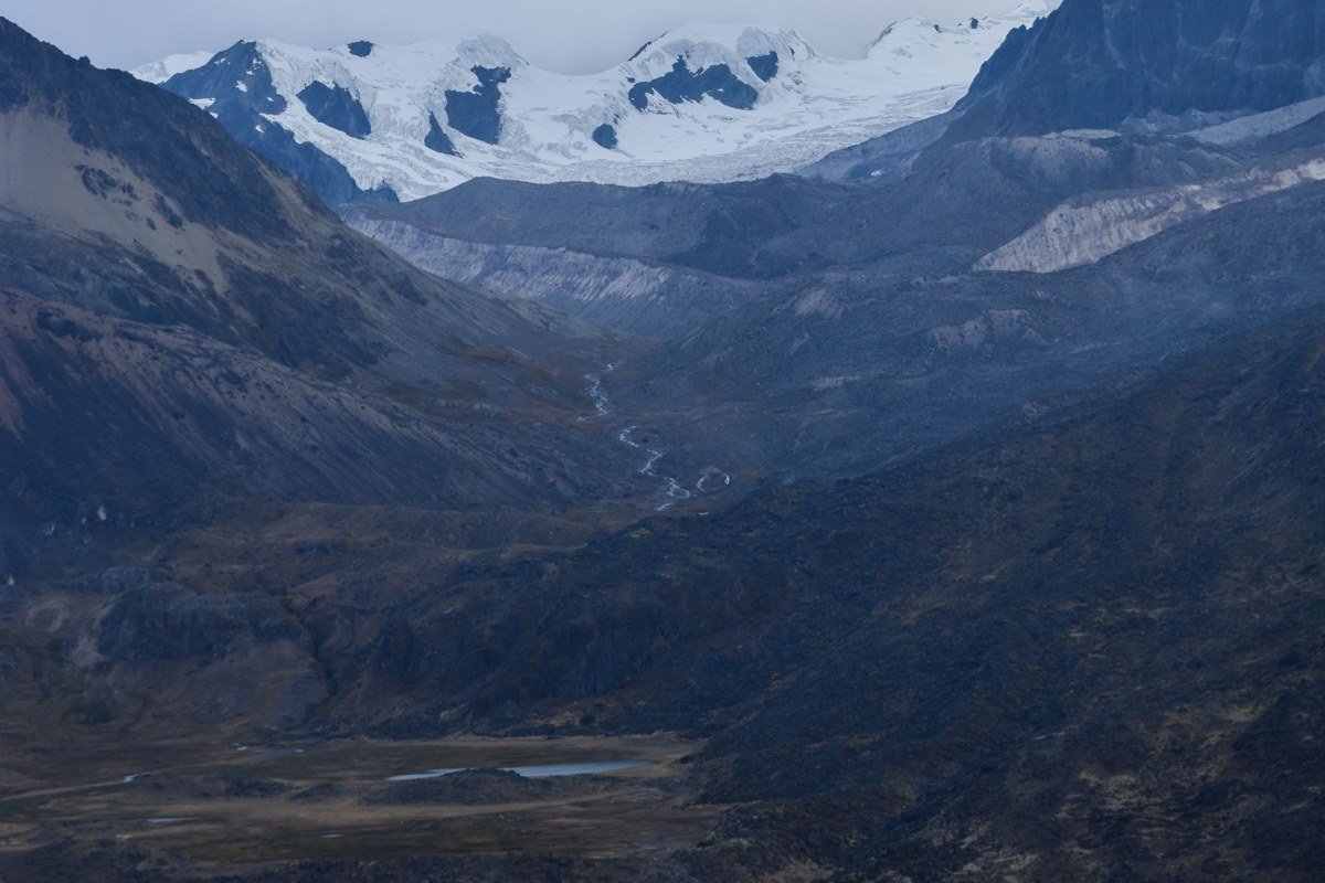 packrafter paddling remote glacier-fed river in Brooks Range Alaska with tundra and mountain peaks in background