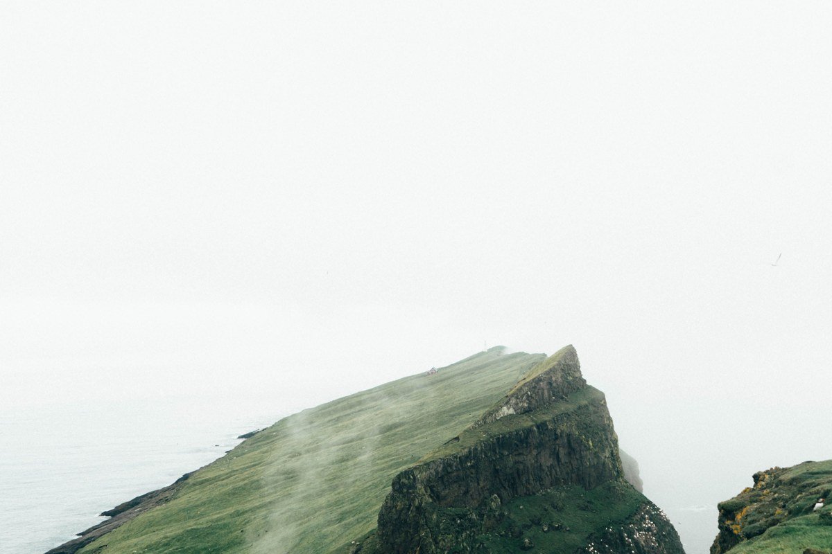 Faroe Islands dramatic fog covered cliffs and green valleys aerial view