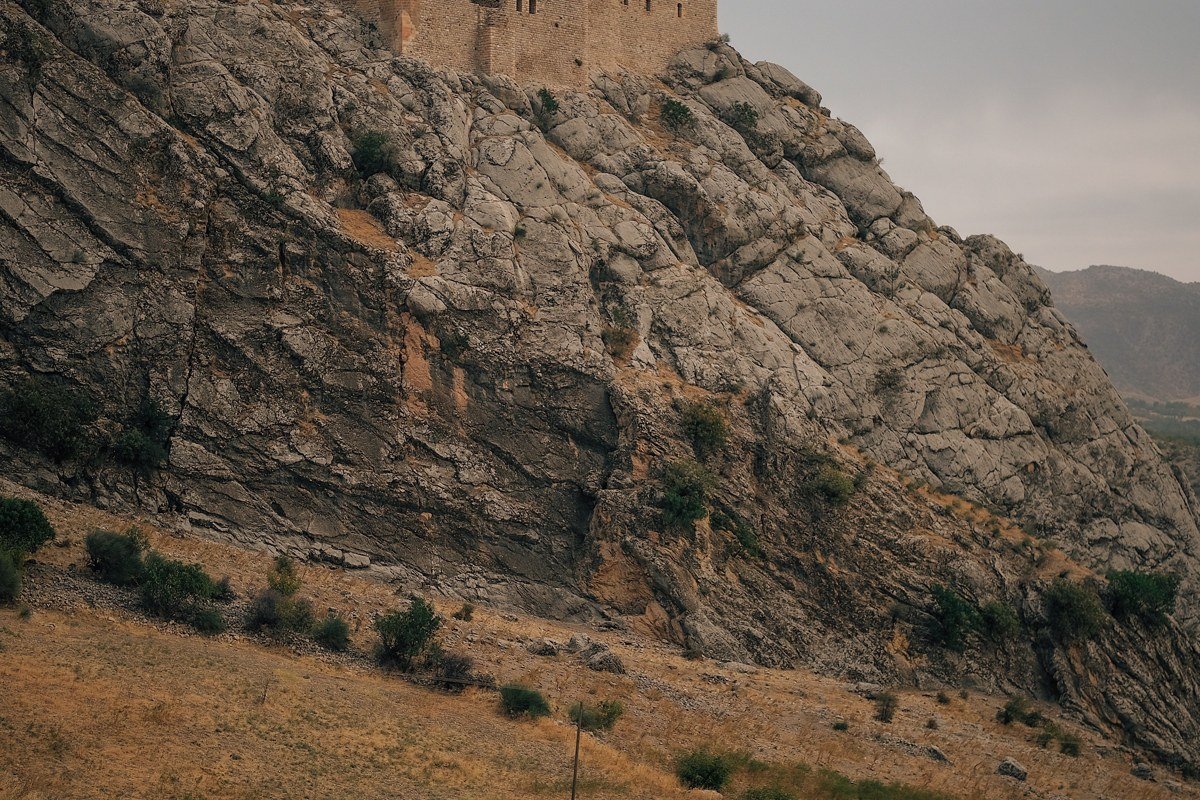 Monemvasia medieval castle town rising from rocky island connected by causeway in golden evening light