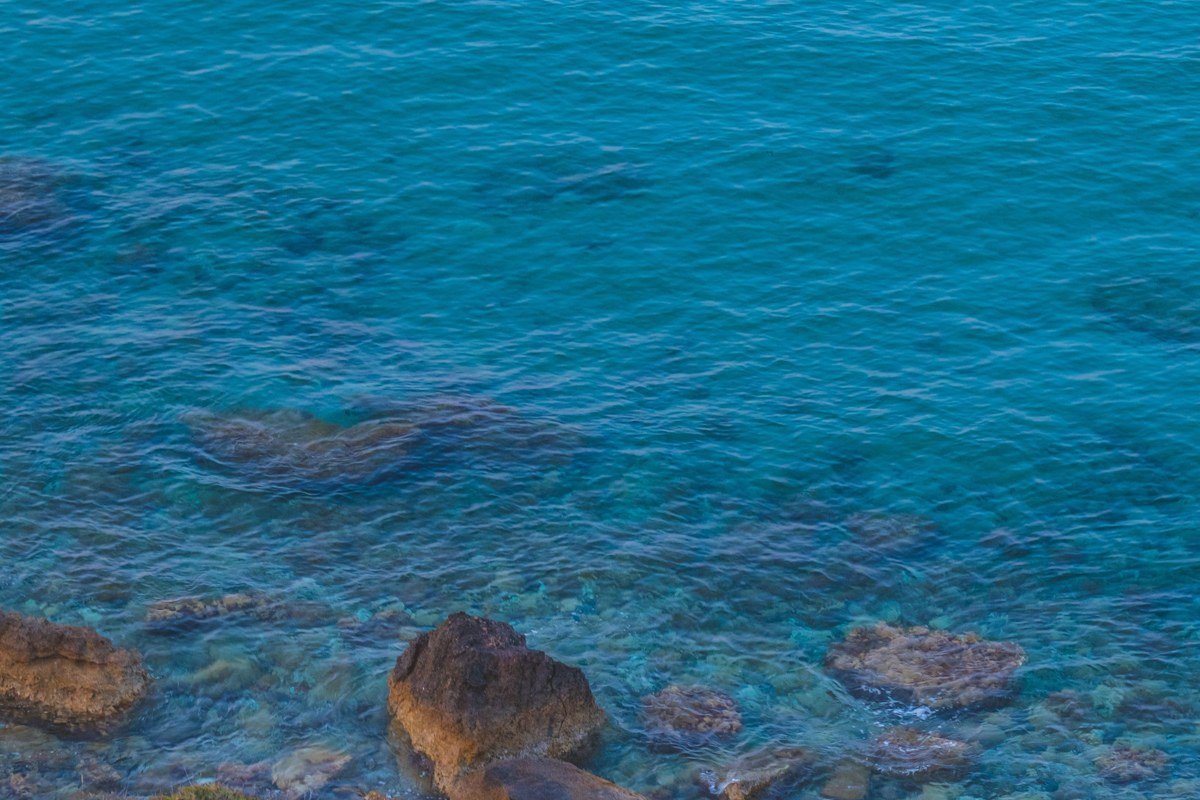 Ikaria Greece lush green hillside terraced village with wild rocky coastline and clear turquoise water