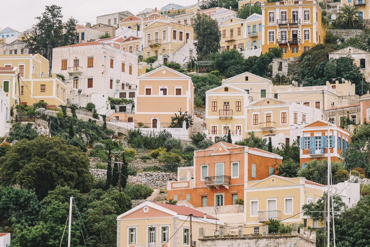 Halki Dodecanese island colourful neoclassical harbourfront mansions reflected in calm harbour water