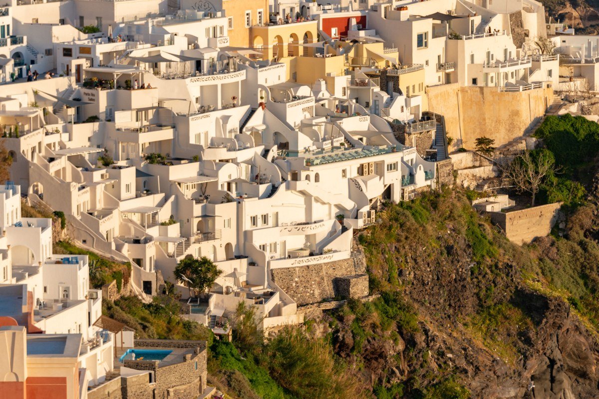 aerial view of whitewashed Greek island village overlooking turquoise Aegean Sea at golden hour