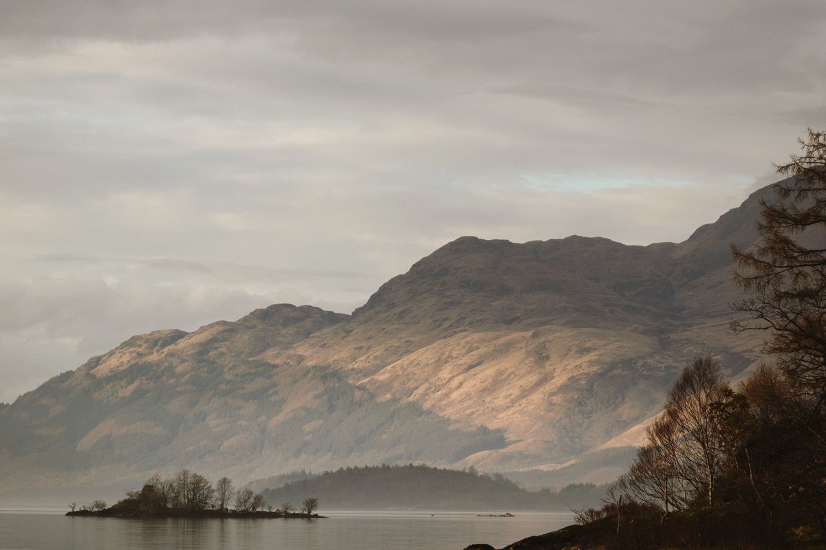 Scotland Highlands misty loch at dawn with mountains reflected in glassy water