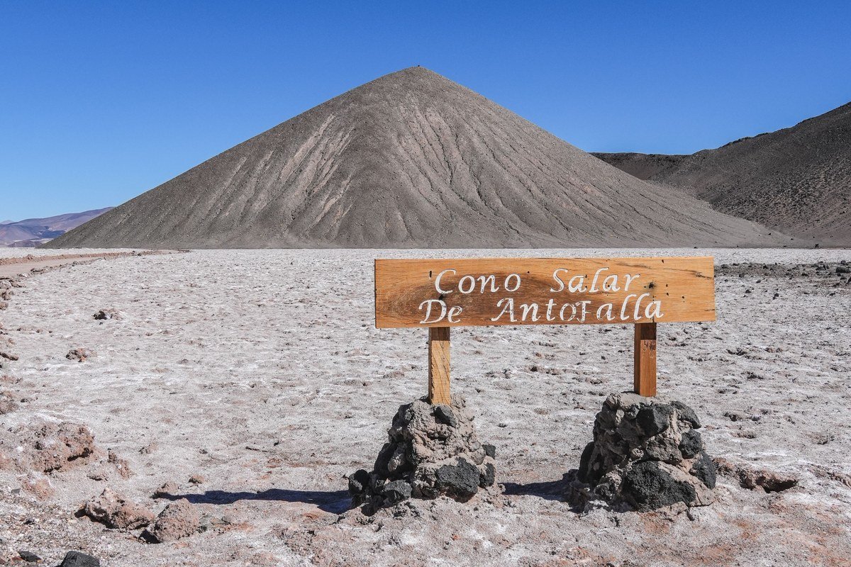 Bolivian altiplano volcanic landscape at golden hour with layered volcanic peaks and salt crust foreground, dry season wide angle