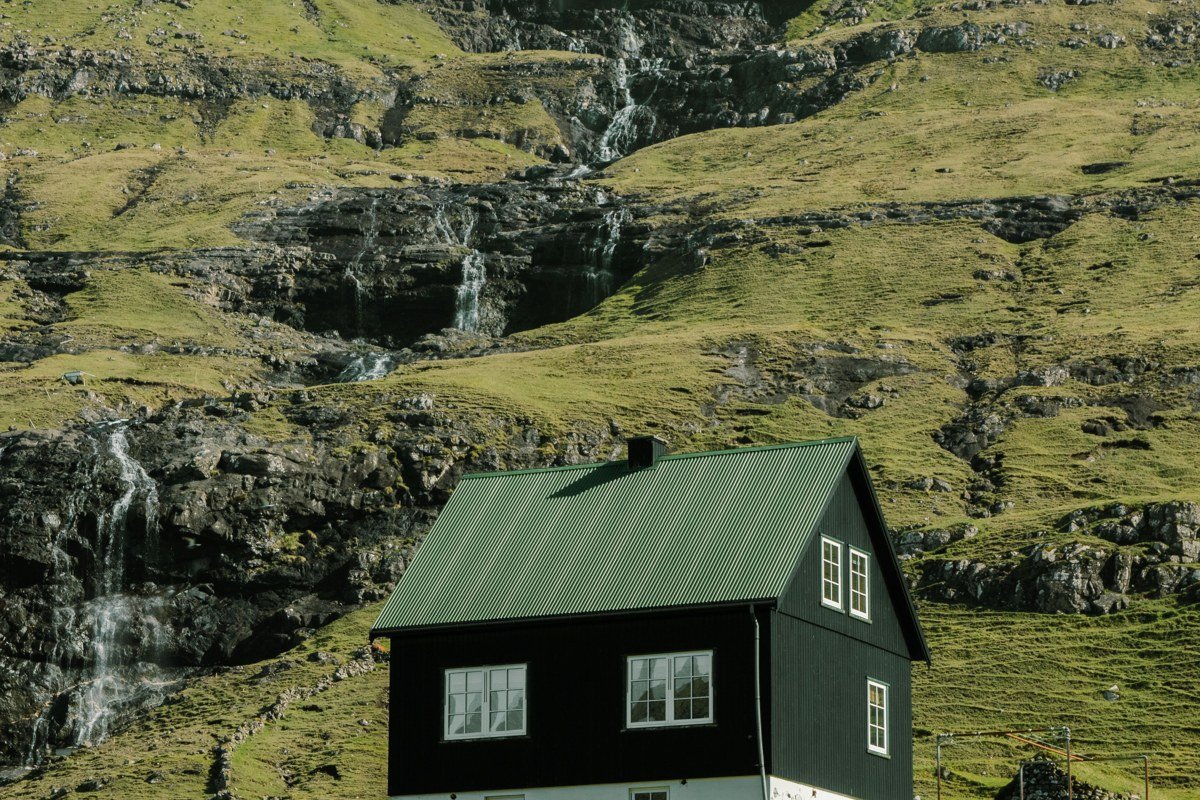 Gasadalur Mulafossur waterfall Faroe Islands village cliff ocean backdrop green grass