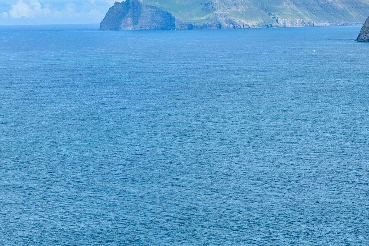 Kallur lighthouse Kalsoy Faroe Islands green ridge sea stacks misty