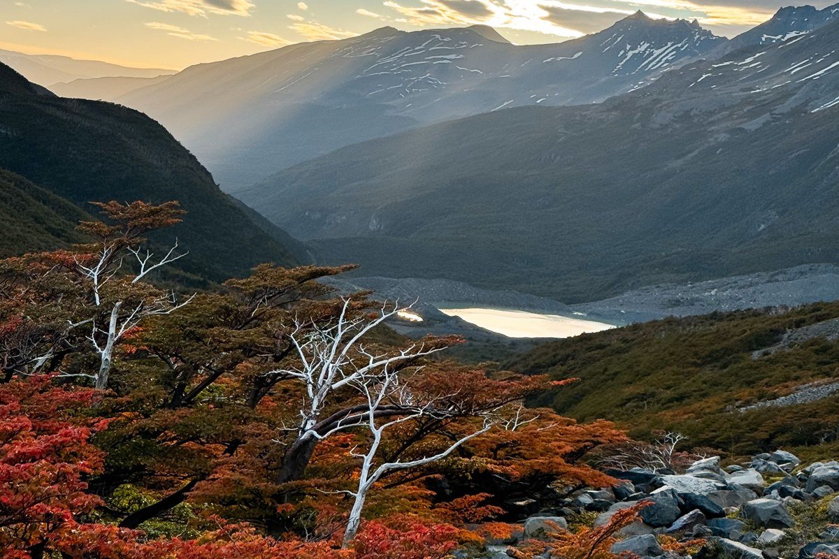 Carretera Austral Chile gravel road river valley autumn forest dramatic clouds motorcycle