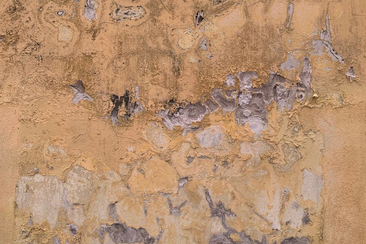 Handpainted interior mural detail from colonial church in Salinas de Garci Mendoza, warm ochre and terracotta pigments, worn plaster surface showing age, natural light from side window
