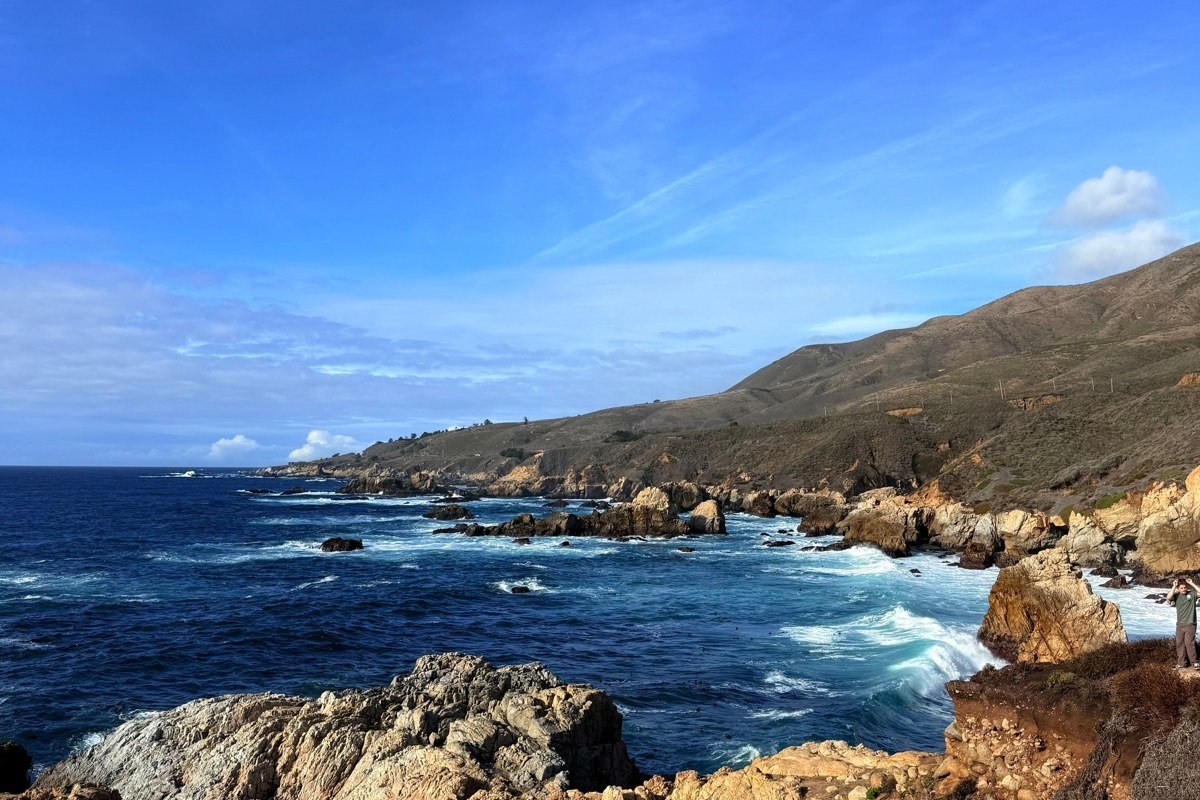 California scenic coastal highway with cypress trees and ocean bluffs at golden hour