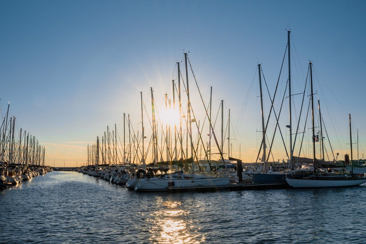 East Coast scenic coastal town harbor at golden hour with sailboats and colorful storefronts