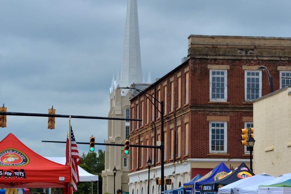 Highlands North Carolina Main Street boutique storefronts summer afternoon with Nantahala National Forest ridge in background and stone walls
