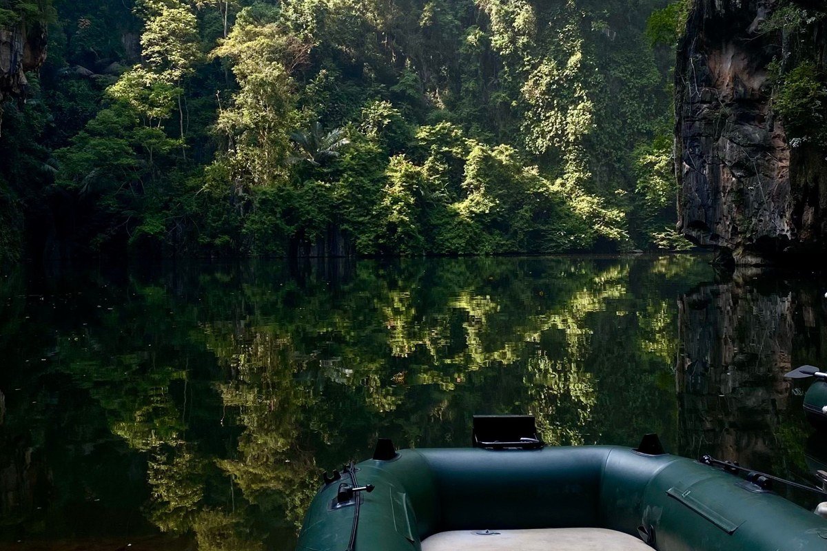 A raft threading the narrow green gorge of the Pacuare River, canyon walls rising thirty meters overhead, mist clinging to the cecropia trees above the waterline