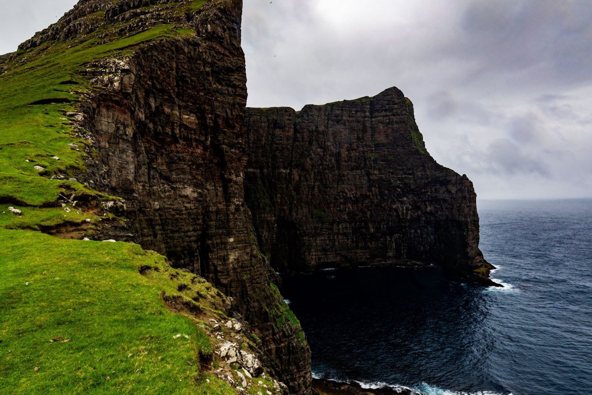 Faroe Islands dramatic fog-covered plateau aerial view green cliffs Atlantic ocean