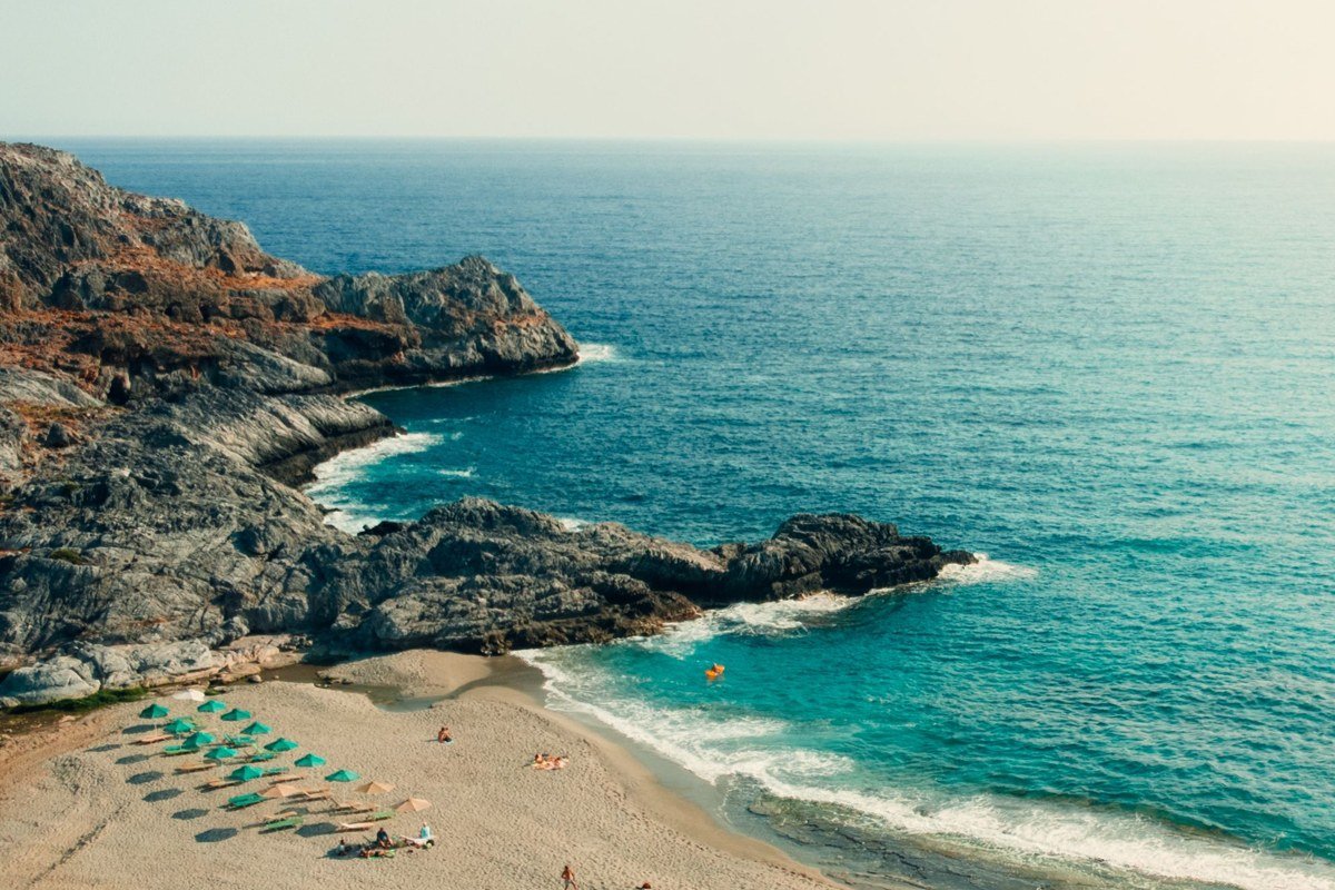 Plakias Crete long sandy beach dramatic mountains backdrop late afternoon
