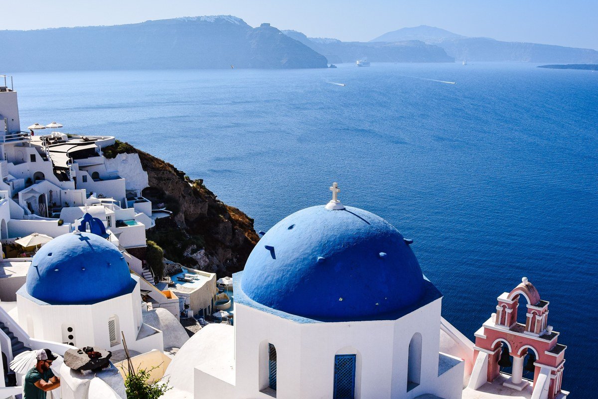 hidden Greek island whitewashed village blue dome turquoise sea aerial view