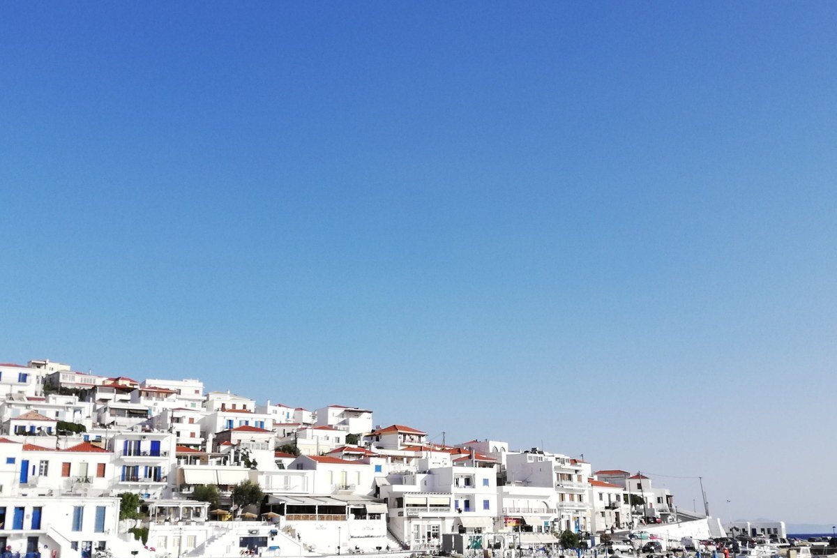Halki island Greece neoclassical pastel harbor mansions clear water