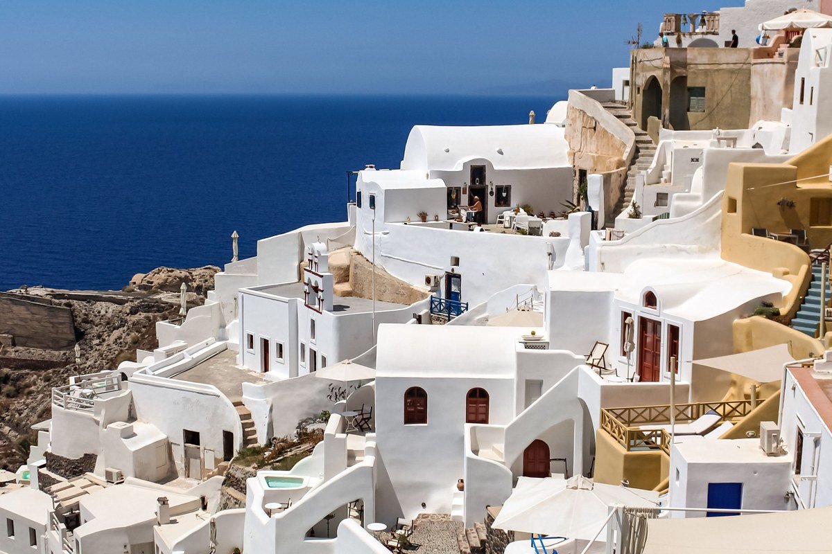 aerial view whitewashed Greek island village blue domed church cliffside Mediterranean sea
