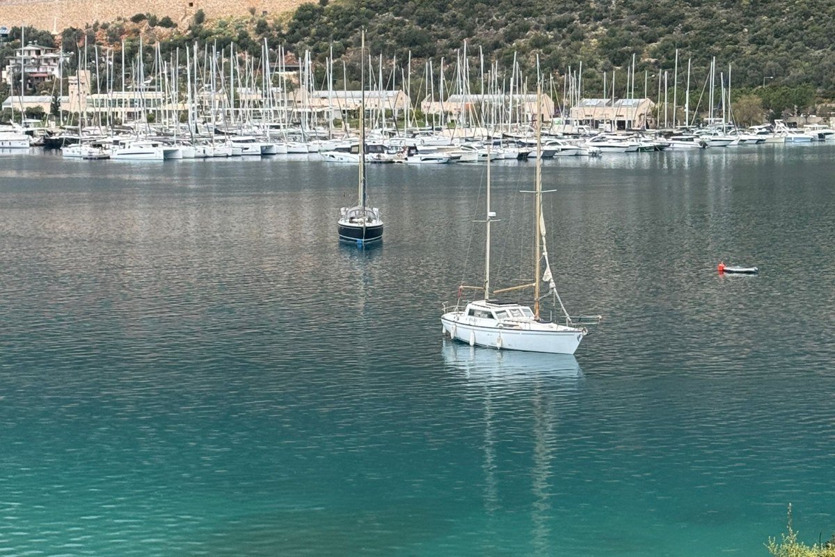 Halki Dodecanese island neoclassical pastel harbor mansions reflection calm turquoise water