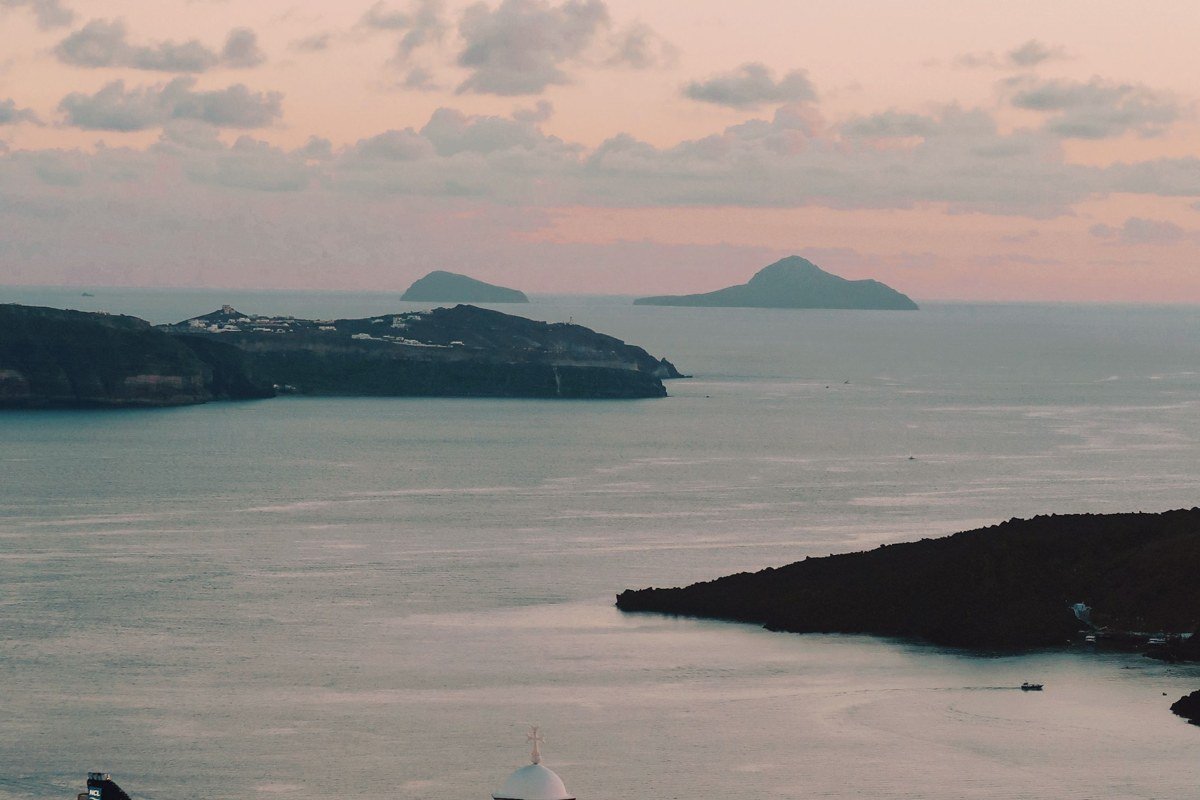 Anafi Greece whitewashed Chora village steps blue church dome volcanic rock cliffs sunset