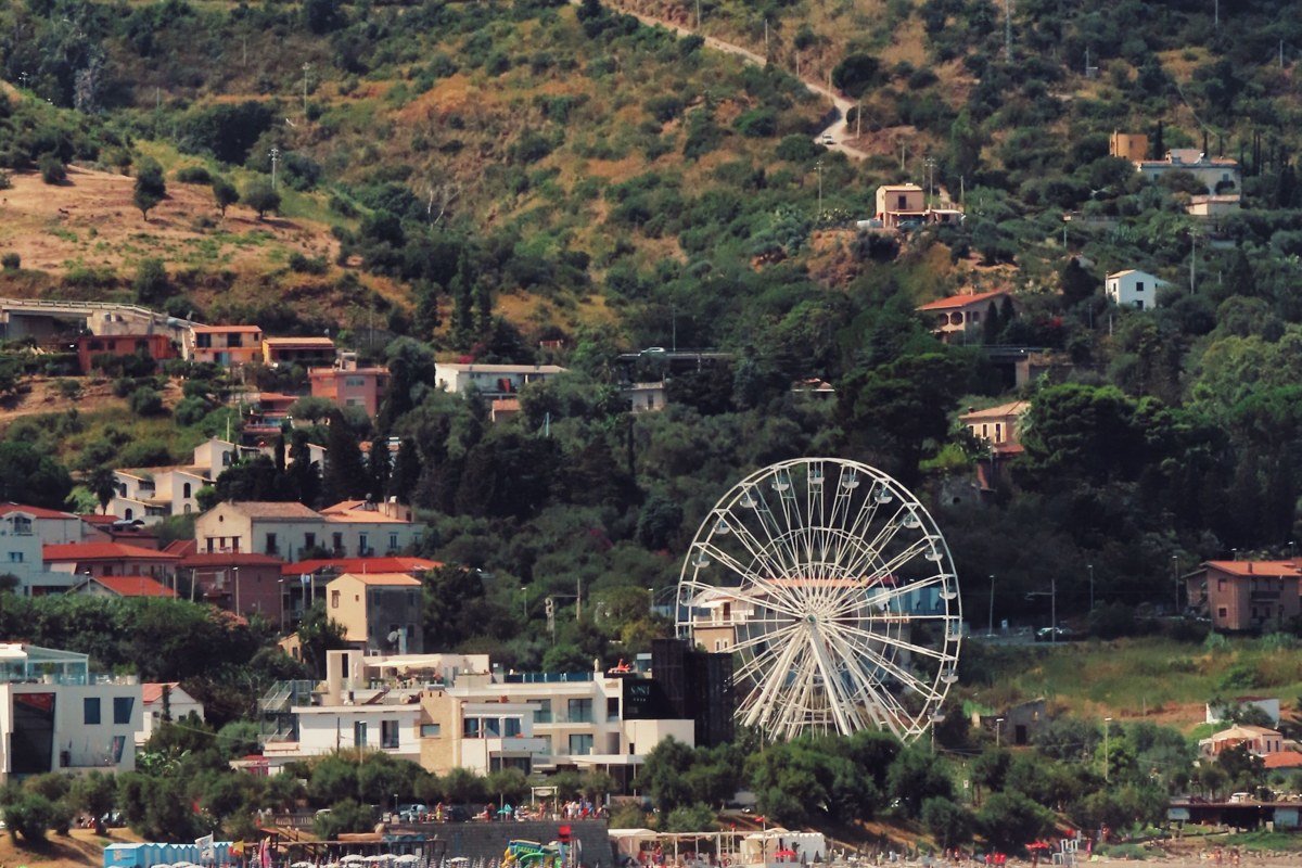 Sperlonga's whitewashed promontory photographed from the beach at Torre Truglia, the stacked cube houses reading as Cycladic from below, almost no one else in the frame on a July morning