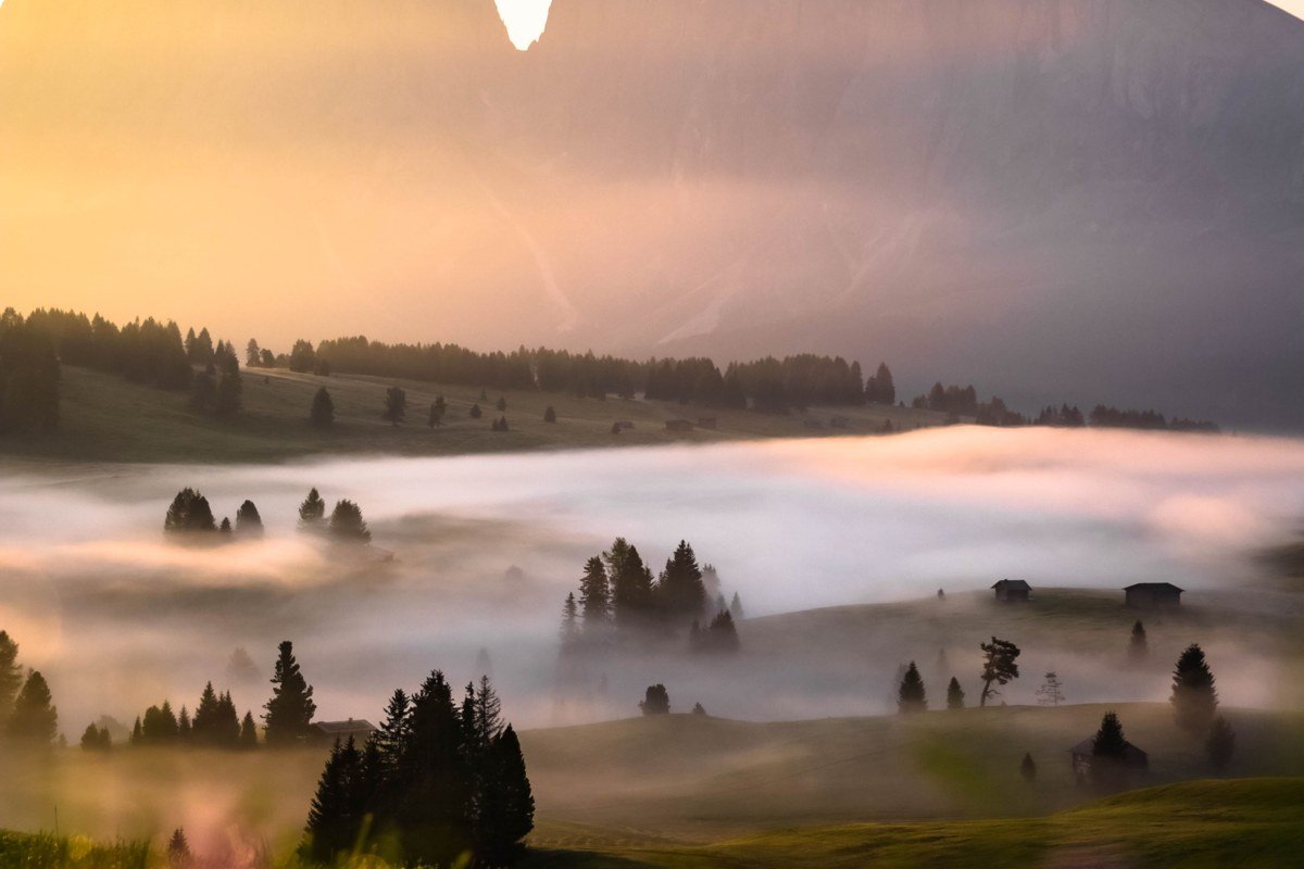misty European valley with ancient ruins and fog rolling through mountains at dawn