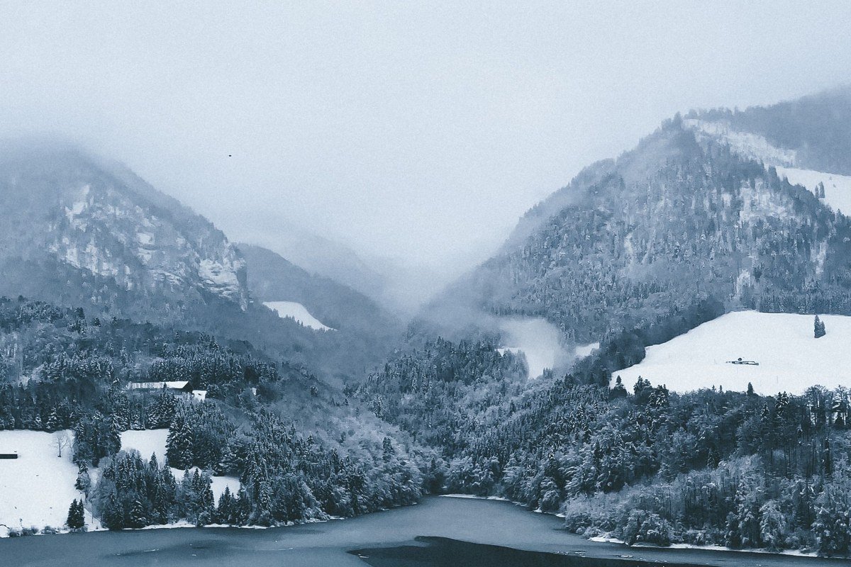 Scottish Highlands winter mist over snow-dusted mountains and glassy loch at dawn