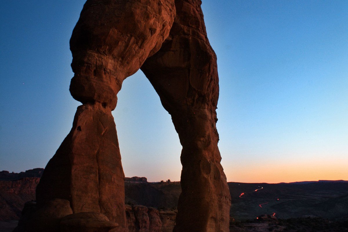 Delicate Arch at sunset with golden sandstone and La Sal Mountains in background, Utah
