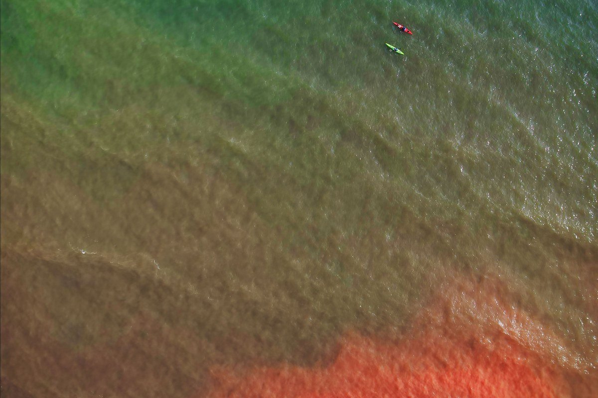 kayaker paddling into a sandstone sea cave at Apostle Islands National Lakeshore Wisconsin, turquoise Lake Superior water
