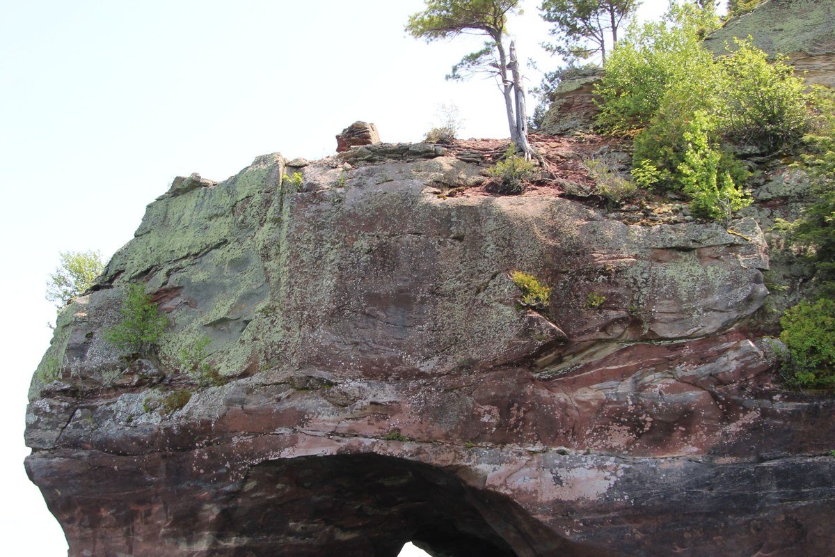 brownstone sea cave arch at Sand Island Apostle Islands with kayak passing through, layered sandstone cliffs