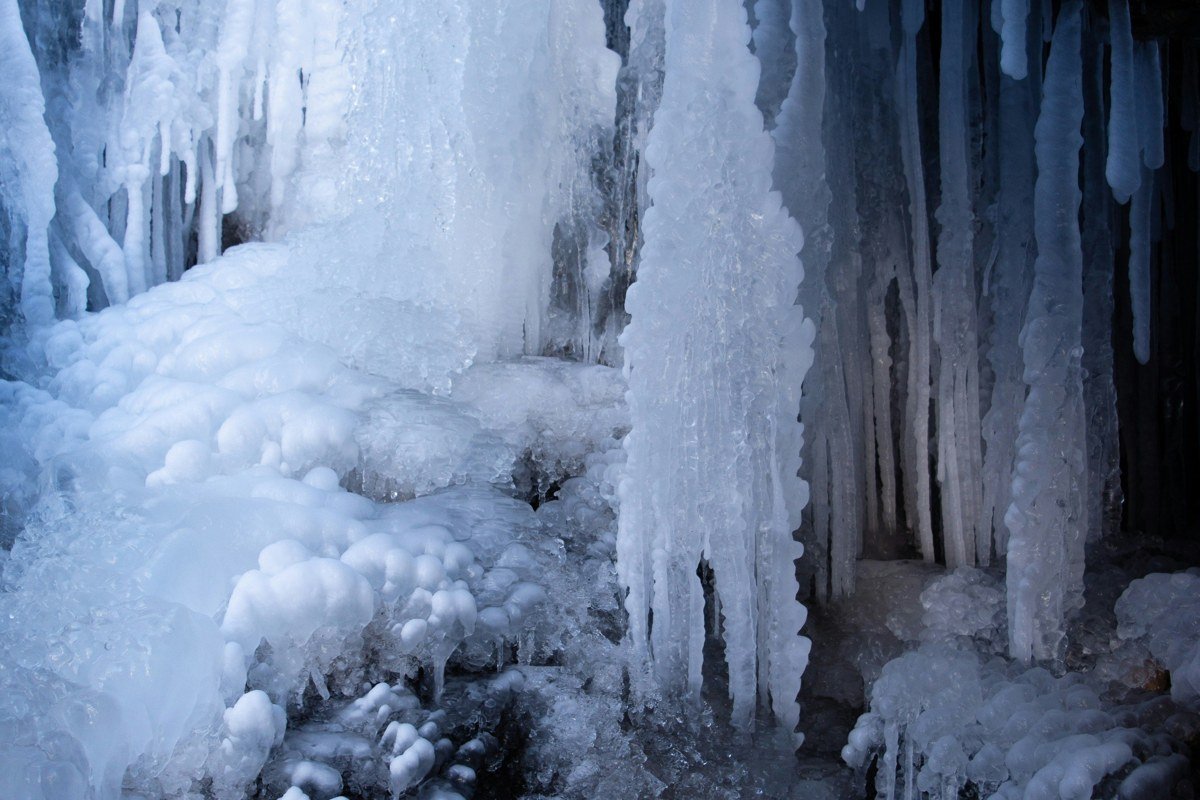 frozen ice formations and icicles at Meyers Beach Apostle Islands ice caves in winter, people walking on frozen Lake Superior