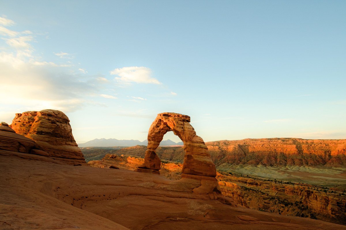sunrise light on red sandstone arch formation with empty trail, Utah desert