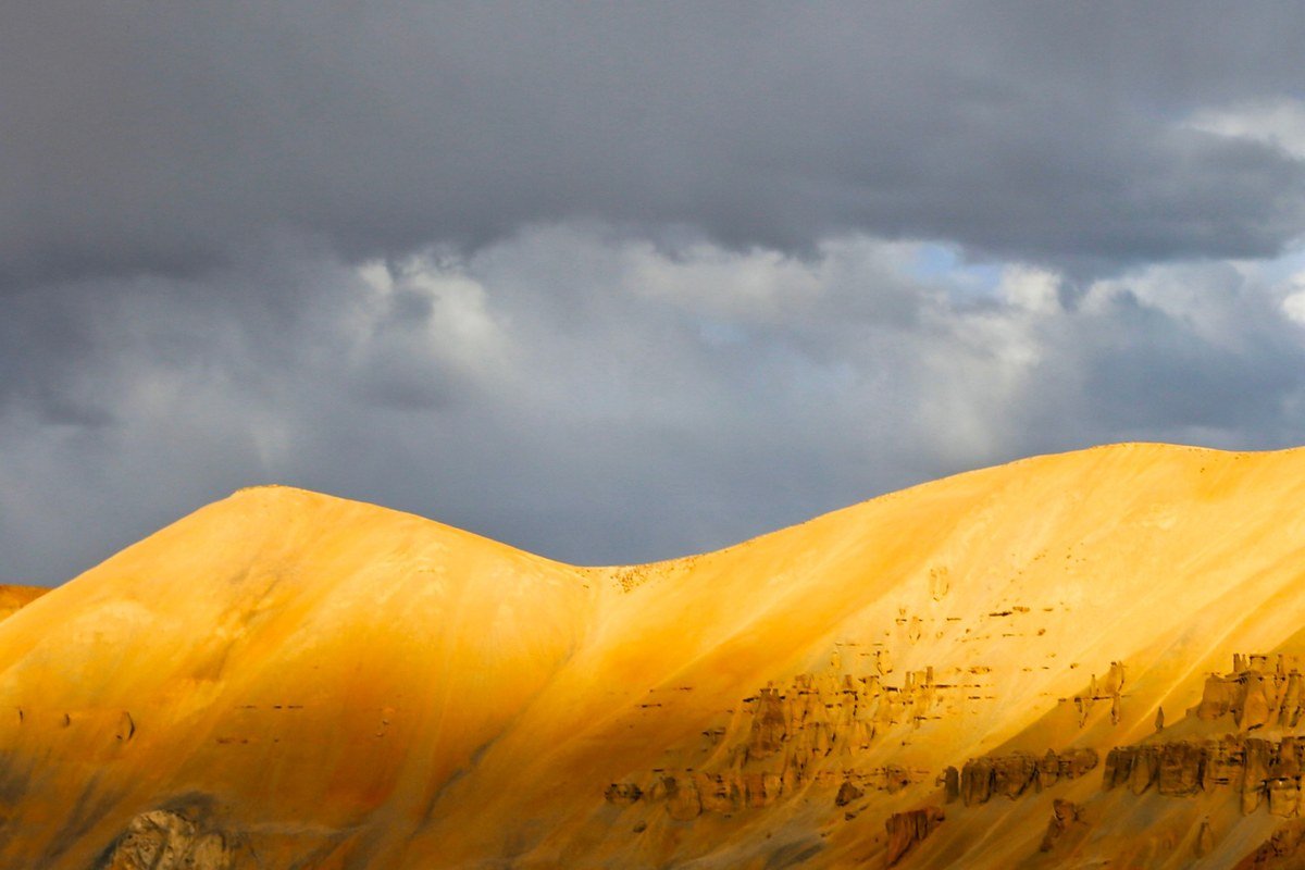 wide golden hour view of layered desert badlands stretching to the horizon under a dramatic sky