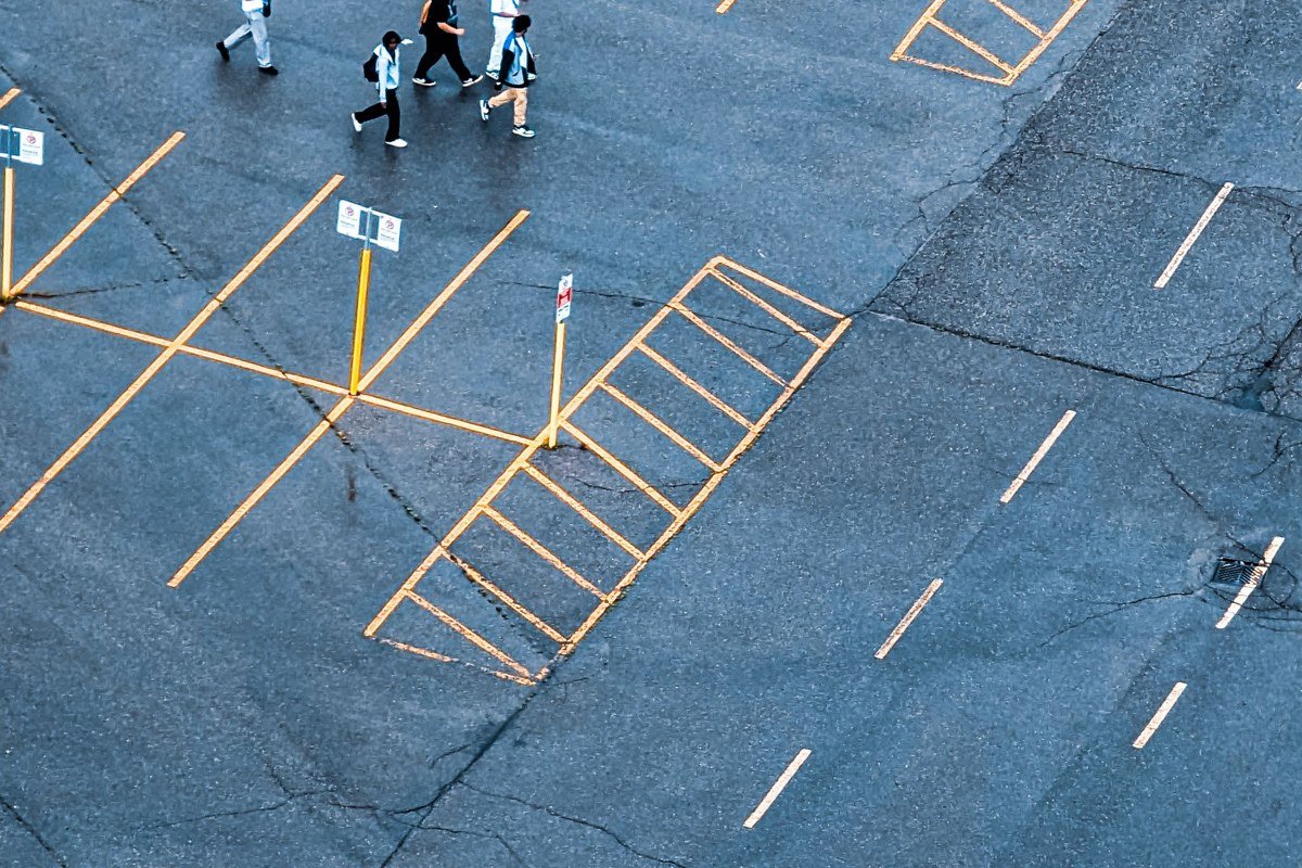 a nearly empty gravel parking lot with a hand-painted ferry schedule sign, one truck parked at the far end