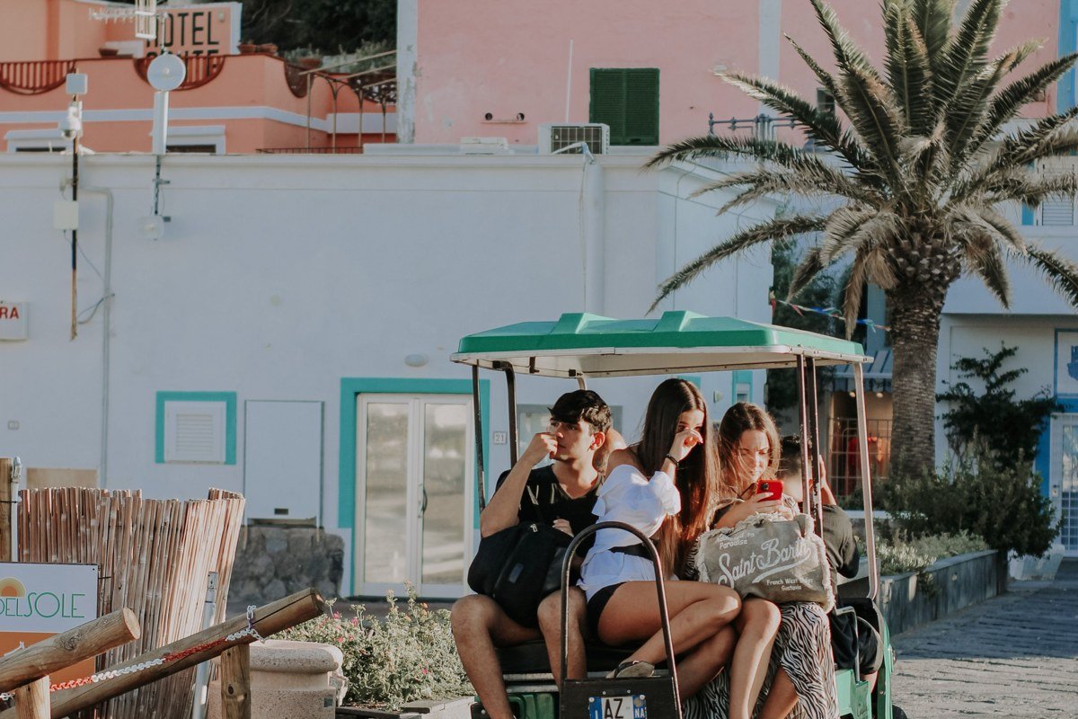 a row of golf carts parked outside a small island grocery store, bikes leaning against the railing