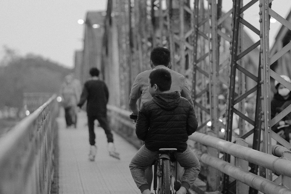 Cape Cod Canal Bikeway with cyclists along the water and a bridge in the background