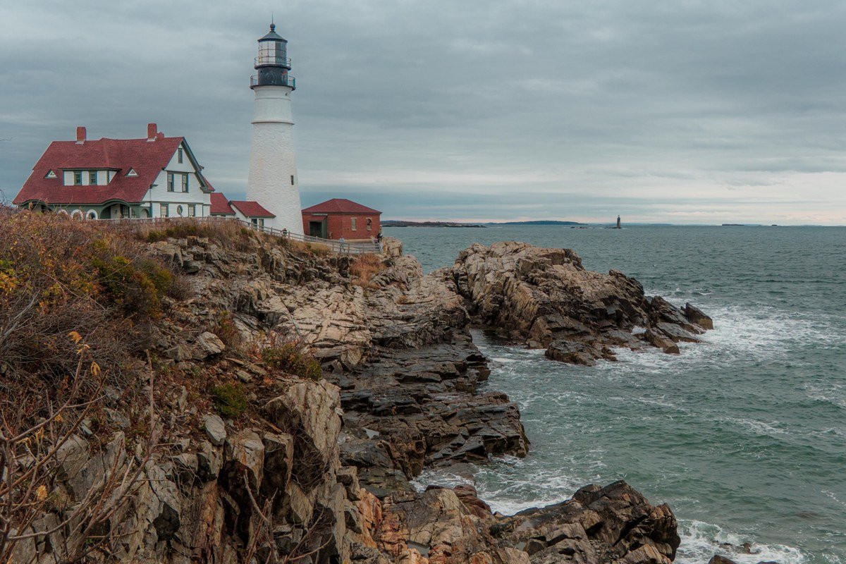 Portland Head Light Cape Elizabeth Maine lighthouse emerging from fog over rocky shore