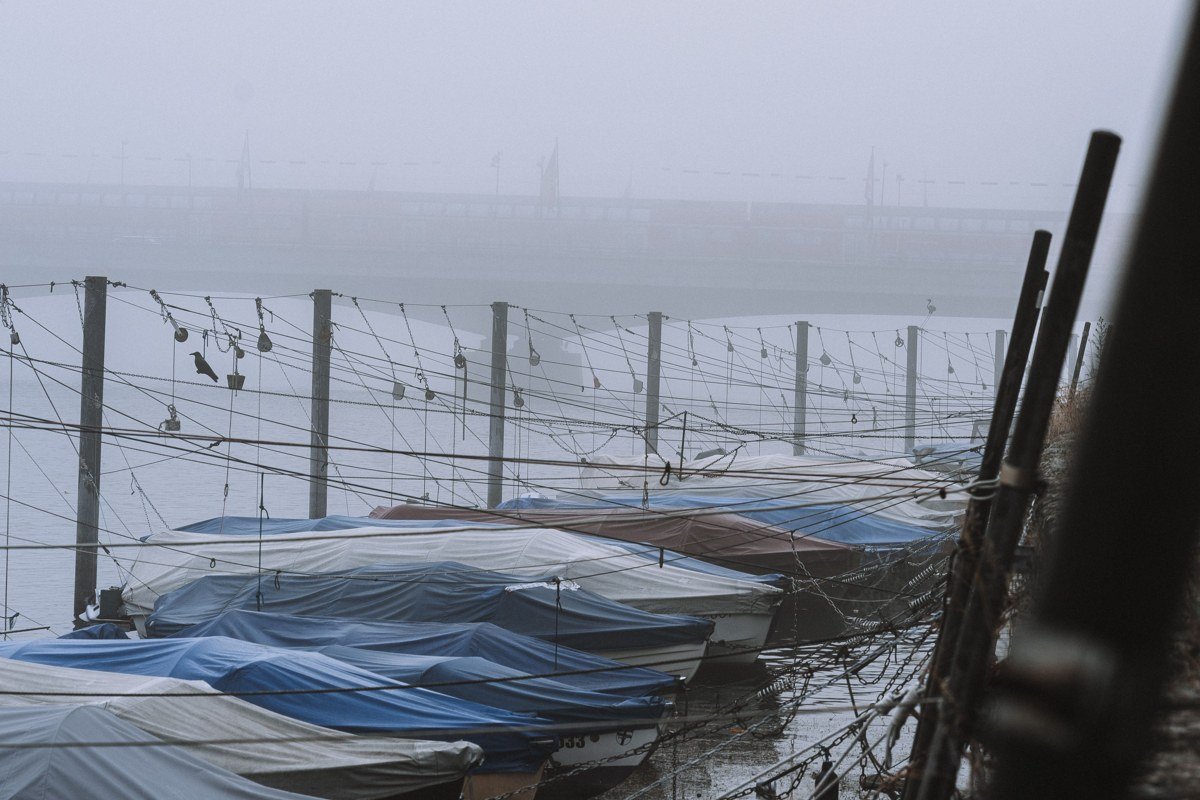 misty Maine coastline at dawn with lobster boats and pine islands fading into gray fog