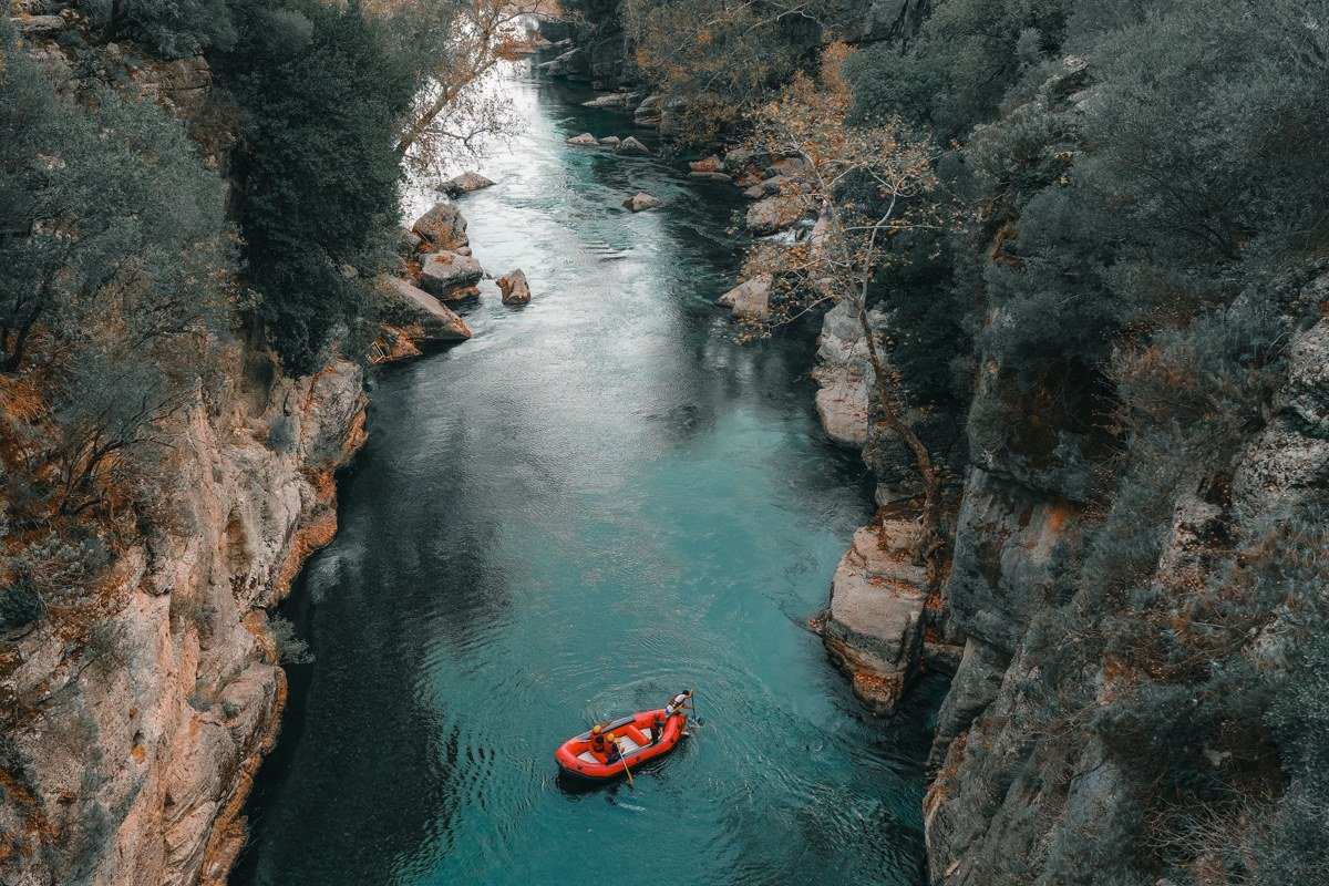 raft floating a calm stretch of the Poudre Canyon, pine forest lining both banks