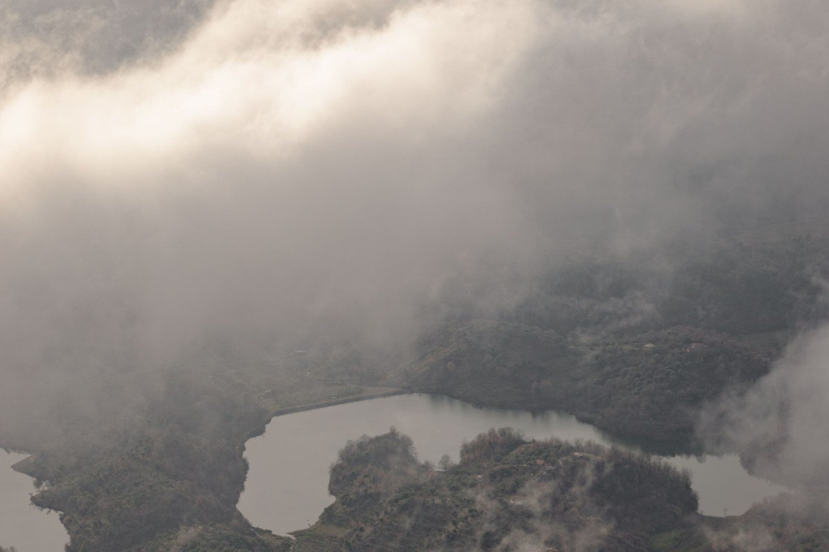 Crater Lake Oregon rim with fog partially covering the deep blue water at sunrise