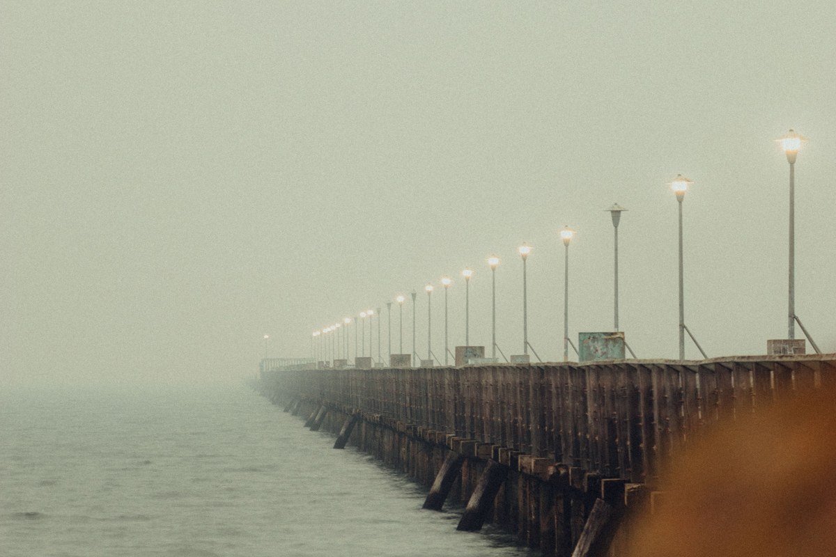Rockland Maine breakwater lighthouse at end of long stone pier in fog