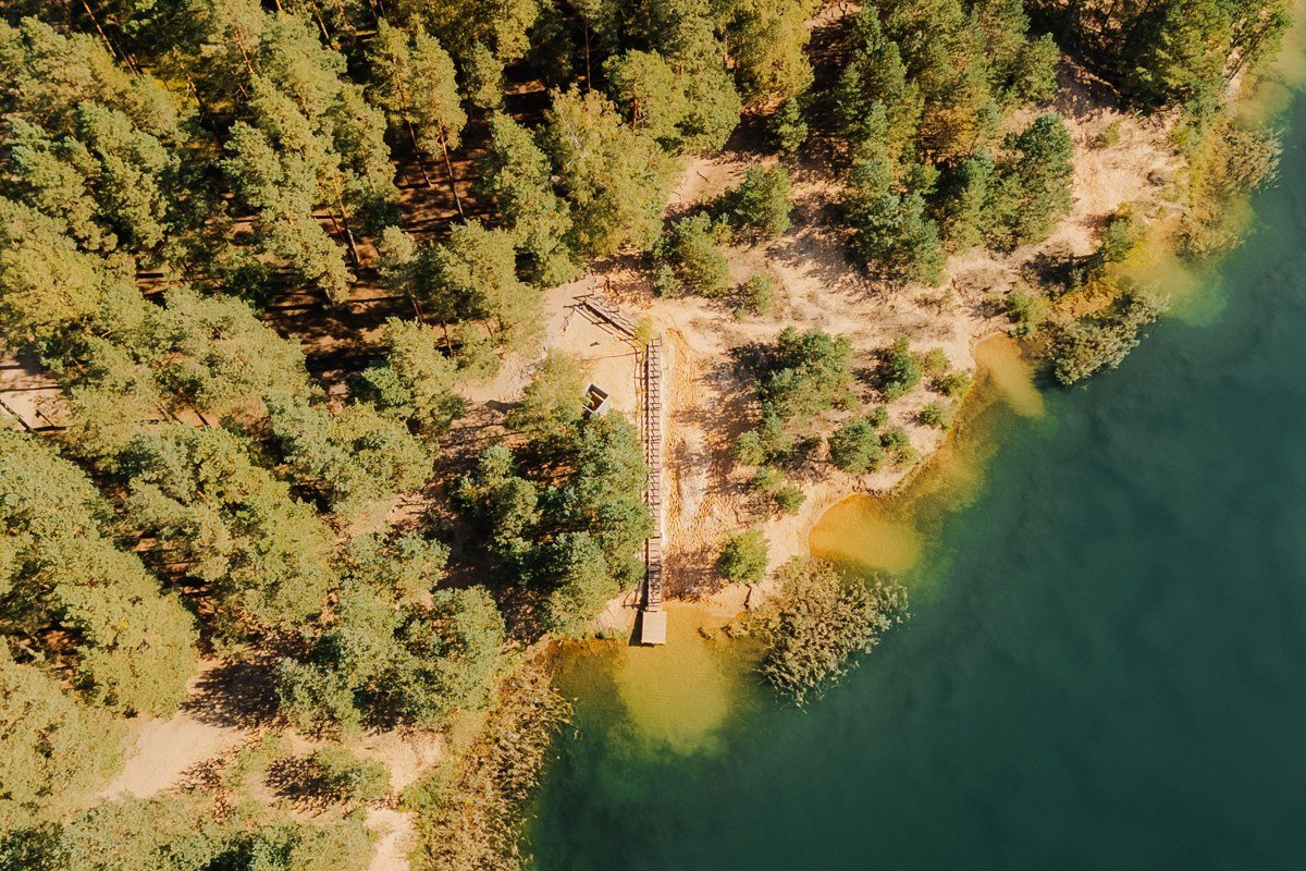 aerial view of an Adirondack lake at golden hour with pine forest shoreline and a single dock