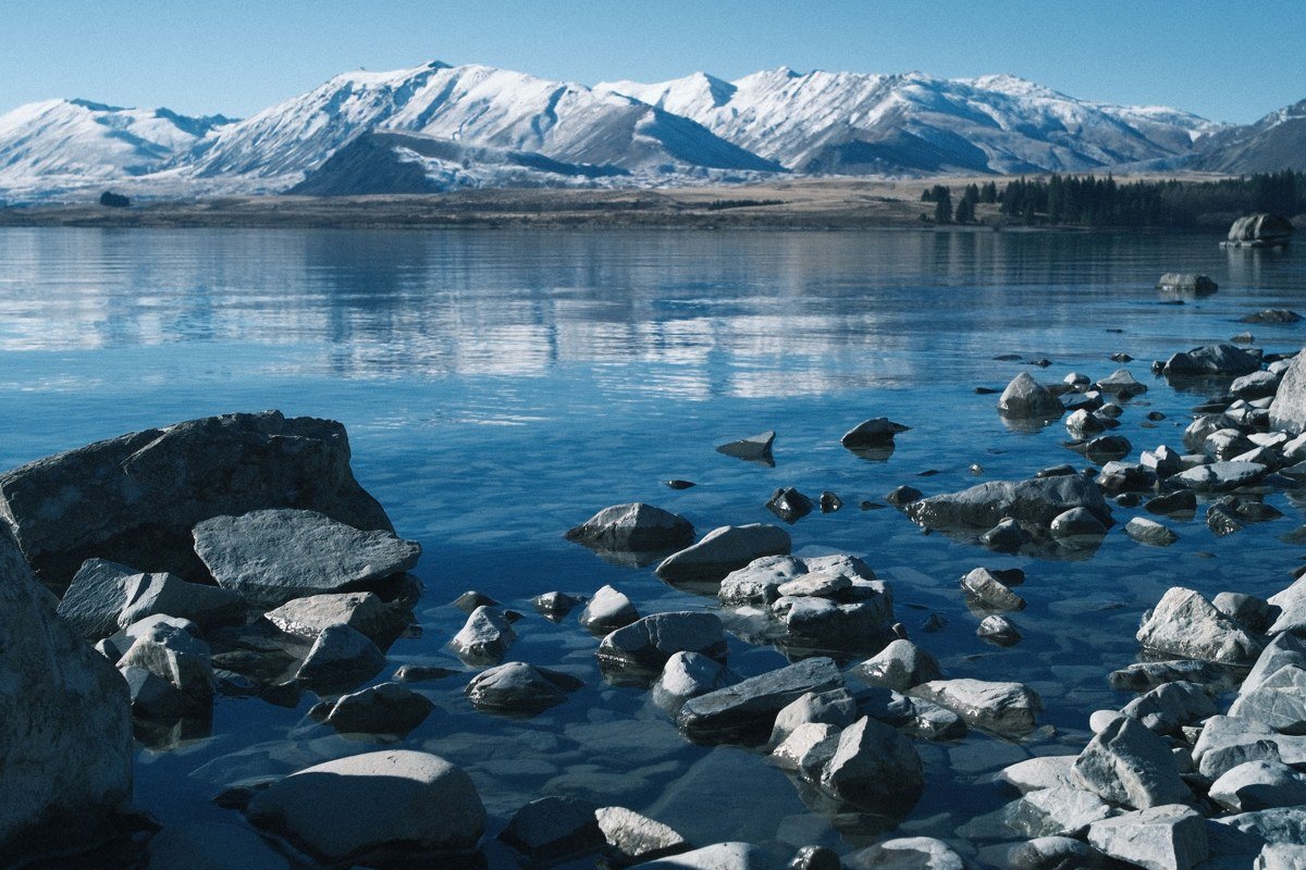 South Lake Tahoe shoreline with snow capped mountains reflected in blue water