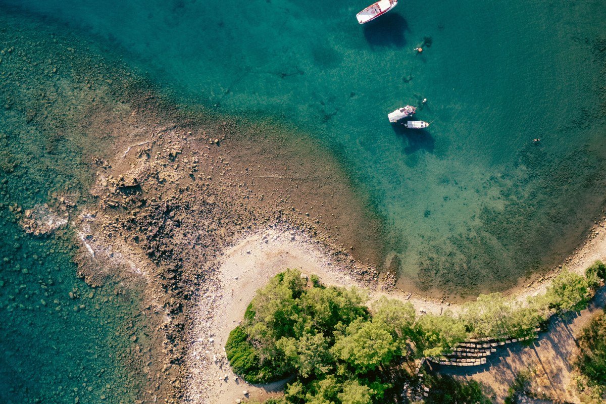 aerial view of a Northeast lake town at sunrise with pine forest shoreline and small boats on calm water