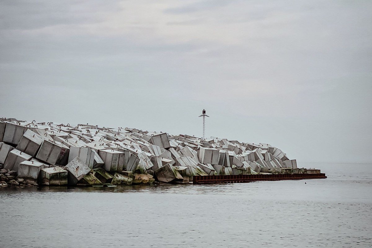 downtown Marquette storefronts and the Marquette Harbor Lighthouse, breakwall fading into gray