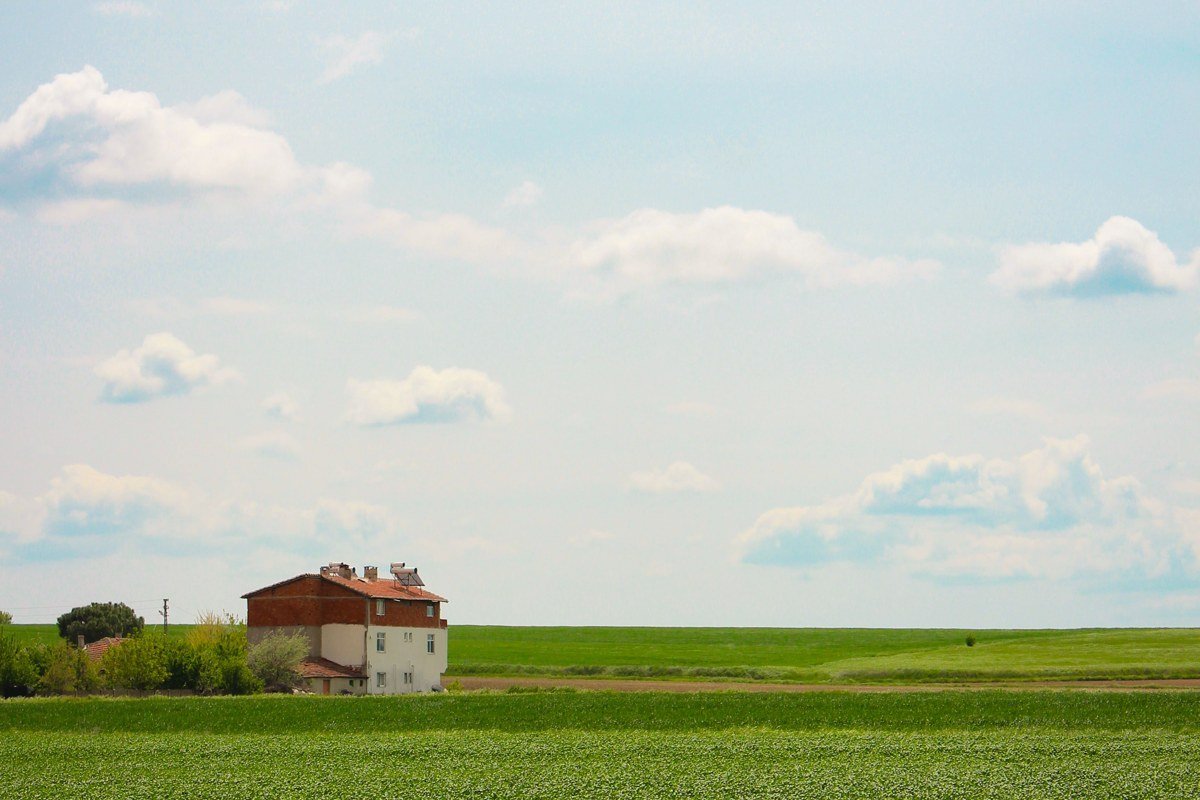 Olson House farmhouse facade, grass field in foreground, matching the Christina's World vantage point